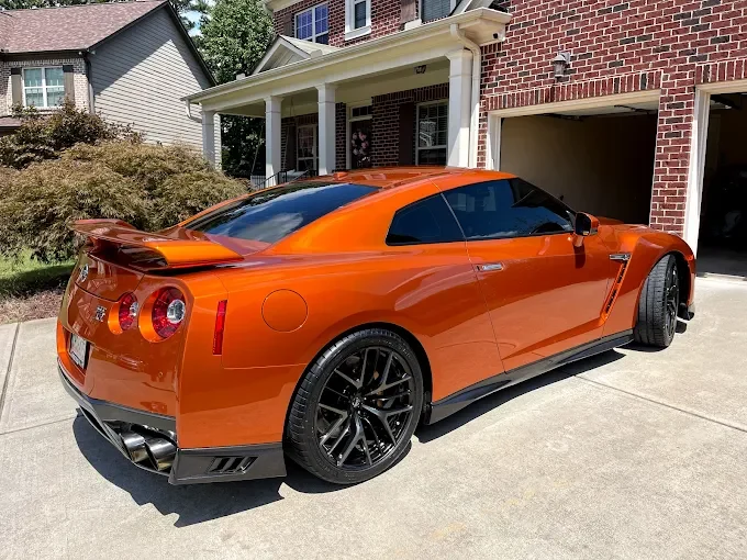 Orange Nissan GT-R in a Sandy Springs driveway showcasing Precision Auto Styling’s premium window tint installation.